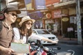 Asian backpack couple tourist standing near to the road waiting for local taxi