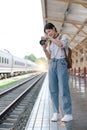 Asian backpack traveler woman with camera standing at train station platform and waiting train arrivel, summer holiday Royalty Free Stock Photo