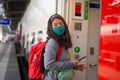 Asian backpacker girl traveling in times of covid19 - young happy and beautiful Korean woman in face mask and backpack waiting for