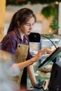 Asian bakery owner woman standing at a table behind a customer\'s cash register. Shopkeepers often wear apron while