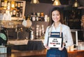 Asian barista holding tabblet sign weÃ¢â¬â¢re open for takeaway orders only infront of counterbar.social distancing concept when