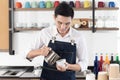 Asian barista man pour the mixed milk into a cup of coffee