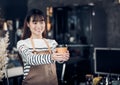 Asian Barista served coffee up with smile at cafe holding mug with two hand with smiling face at cafe bar background Royalty Free Stock Photo