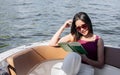 Asian beautiful adorable young woman reading book, wearing casual shirt and sunglasses, sitting on boat or ship for traveling Royalty Free Stock Photo