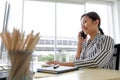 An asian beautiful business woman wearing casual striped pattern shirt, smiling with happiness and talking on mobile or smart Royalty Free Stock Photo