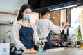 Asian beautiful Coffee shop owner clean counter bar and wiping on machine with sanitizer spray. Young waitress and waiter couple d Royalty Free Stock Photo