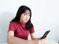 Asian beautiful girl is reflect and think by looking outward in the smartphone on the isolated white background