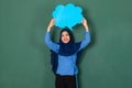 Asian beautiful happy smiley Muslim woman wearing blue hijab standing confidently and holding blue copy space speech bubble over Royalty Free Stock Photo