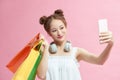 Asian beautiful happy young woman holding smartphone for selfie and shopping online with shopping bags on pink background Royalty Free Stock Photo