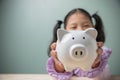 Asian beautiful little cute kid girl holding the white piggy bank with copy space. Savings money for education to the future. Royalty Free Stock Photo