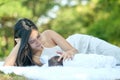 Asian beautiful mother touch and take care her newborn baby who lie on white carpet in the garden Royalty Free Stock Photo