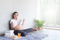 Asian beautiful pregnant woman resting and reading a book while sitting on the floor in living room. Royalty Free Stock Photo