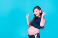 Asian beautiful pregnant woman stands relaxed and enjoys listening to music on headphones connected to the internet