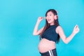 Asian beautiful pregnant woman stands relaxed and enjoys listening to music on headphones connected to the internet