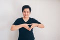 Asian beautiful short hair girl wear black shirt is making heart with fingers or triangle sign  white background. Royalty Free Stock Photo