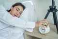 Asian beautiful tired young woman turn off an alarm clock in morning. Attractive sleeping girl in pajamas feel lazy and sick to Royalty Free Stock Photo