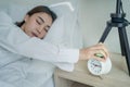 Asian beautiful tired young woman turn off an alarm clock in morning. Attractive sleeping girl in pajamas feel lazy and sick to Royalty Free Stock Photo