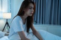 Asian beautiful upset depressed girl sitting alone on bed in bedroom. Attractive unhappy young woman feel sad lonely and upset