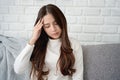 Asian beautiful upset depressed girl sitting aloneon sofa. Unhappy young woman feeling very sad, lonely and stress and headach Royalty Free Stock Photo