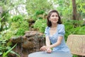 Asian beautiful woman in a blue dress is sitting happily smiling on the green garden and waterfall background Royalty Free Stock Photo