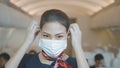 An Asian beautiful woman cabin crew is wearing protective mask onboard , taking of face mask and smiling , safe travel , COVID-19