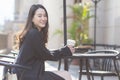 Asian beautiful woman in a dark blue suit is sitting in a chair holding a coffee cup smiling looking at In front of the coffee Royalty Free Stock Photo