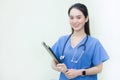 Asian beautiful  woman doctor standing smiling in a blue lab shirt, holding patient documents in hand. Royalty Free Stock Photo