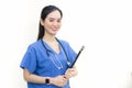 Asian beautiful  woman doctor standing smiling in a blue lab shirt, holding patient documents in hand. Health care concept Royalty Free Stock Photo