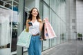 Woman holding shopping bag and smartphone on her hands near the mall shop window Royalty Free Stock Photo