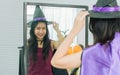 Asian beautiful woman looking at mirror, dressing up and wearing witch costume for celebrating Halloween party, smiling with Royalty Free Stock Photo