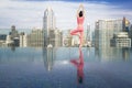 Asian beautiful woman in pink sports uniform doing a yoga exercise on hotel rooftop