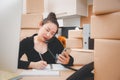 Asian beautiful woman Receiving order by phone and notebooks in selling products online Royalty Free Stock Photo