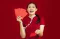 Asian beautiful woman in red traditional chiness dress holding and giving red envelope for bonus and gift red background