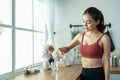 Asian beautiful woman in sportswear drink water after exercise at home. Young thirsty active sport girl takes a sips of clean mine