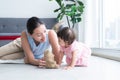 Asian beautiful young mother and Caucasian 7 months baby newborn girl playing with Bear doll toy. Single mom lying on floor Royalty Free Stock Photo