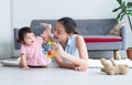 Asian beautiful young mother and Caucasian 7 months baby newborn girl playing with development toy and bear doll. Single mom lying Royalty Free Stock Photo