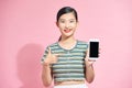 Asian beautiful young woman holding smartphone and pointing finger on mobile phone with smiley face Royalty Free Stock Photo