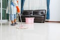 Asian beautiful young woman in protective gloves using a flat wet-mop while cleaning floor in the house, The housekeeper uses a