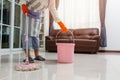 Asian beautiful young woman in protective gloves using a flat wet-mop while cleaning floor in the house, The housekeeper uses a Royalty Free Stock Photo