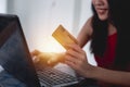 Asian beautiful young woman sitting on the sofa in the living room she is cheerful smiling and hand holding a credit card and usin Royalty Free Stock Photo