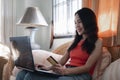 Asian beautiful young woman sitting on the sofa in the living room she is cheerful smiling and hand holding a credit card and usin Royalty Free Stock Photo