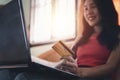 Asian beautiful young woman sitting on the sofa in the living room she is cheerful smiling and hand holding a credit card and usin Royalty Free Stock Photo