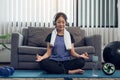 Asian beautiful young woman using smartphone and headphones while meditating and practicing yoga at home Royalty Free Stock Photo