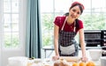 Asian beautiful young woman wearing apron, cooking alone and threshing flour for making bread bakery in cozy kitchen at home on Royalty Free Stock Photo