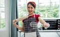 Asian beautiful young woman wearing apron, cooking alone and threshing flour for making bread bakery in cozy kitchen at home on Royalty Free Stock Photo