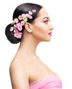 Asian Beauty Girl with Pink Sakura Flowers in Bridal Hairstyle. Woman Profile with Black Hair Bun over White. Fashion Model