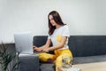 Asian beauty sitting on couch andworking on laptop from home