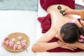 Asian beauty woman lying down on massage bed with traditional hot stones along the spine at Thai spa and wellness center, so relax Royalty Free Stock Photo