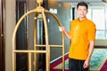 Asian bell boy or porter bringing suitcase to hotel room