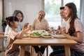 Asian Big happy family spend time have lunch on dinner table together. Little kid daughter enjoy eating foods with father, mother